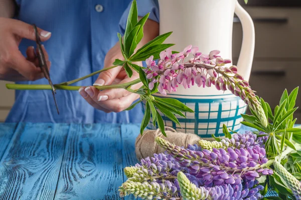 Wanita muda kaukasia mengatur bunga dalam vas di dapur — Stok Foto