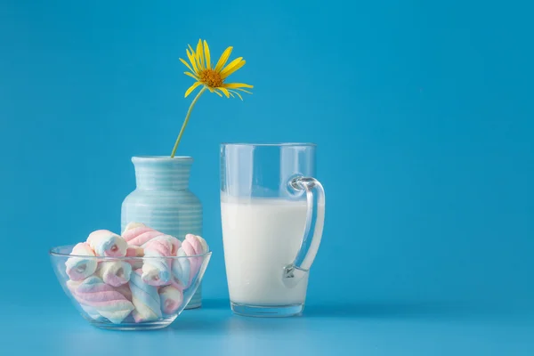 Leche y malvavisco retorcido sobre mesa azul brillante — Foto de Stock