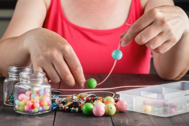 Woman making necklace from colorful beads clipart
