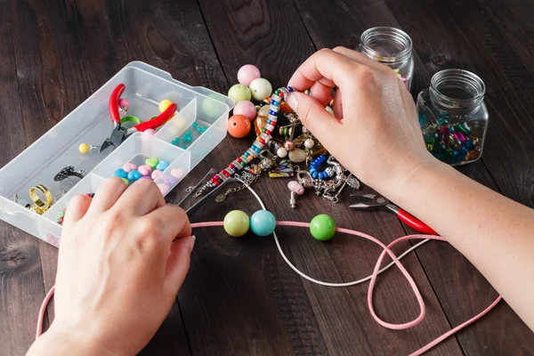 Pair of hands and pliers assembling a bead necklace. — Stock Photo, Image