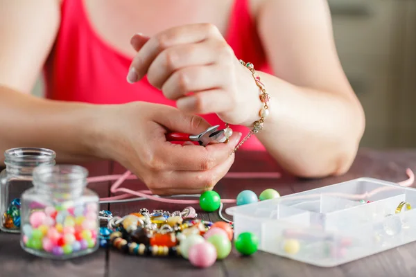 Womans hands making bracelete with plastic beads — Stock Photo, Image