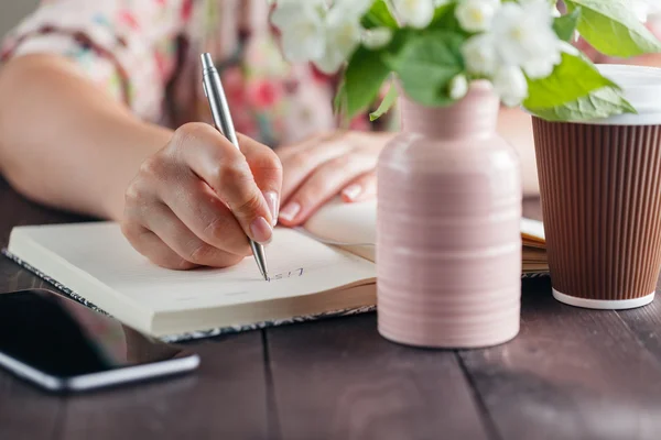 Женщина работает за столом с цветами букет Ана забрать кофе — стоковое фото