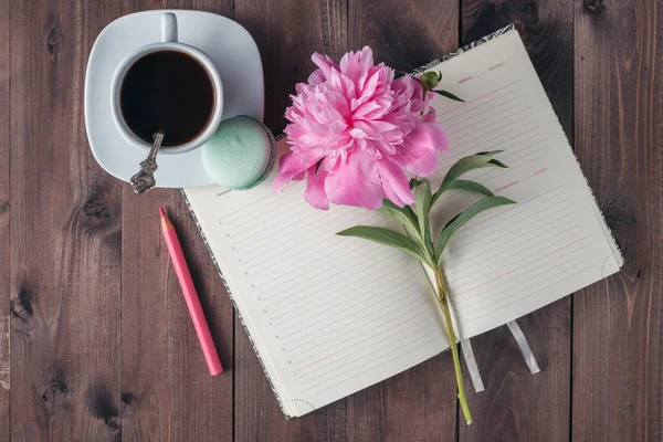 Ahşap arka plan üstünde defter ile kahve