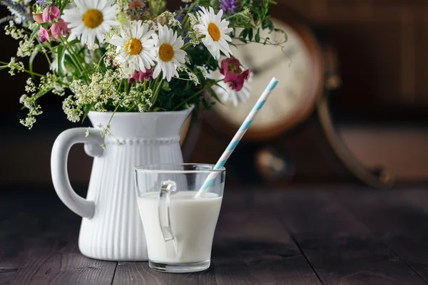 Kopp mjölk med bukett av blommor — Stockfoto