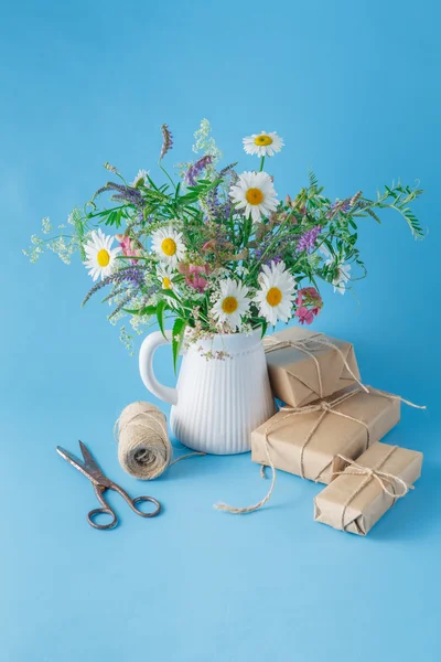 Caja de regalo hecha a mano con flores silvestres sobre fondo azul —  Fotos de Stock