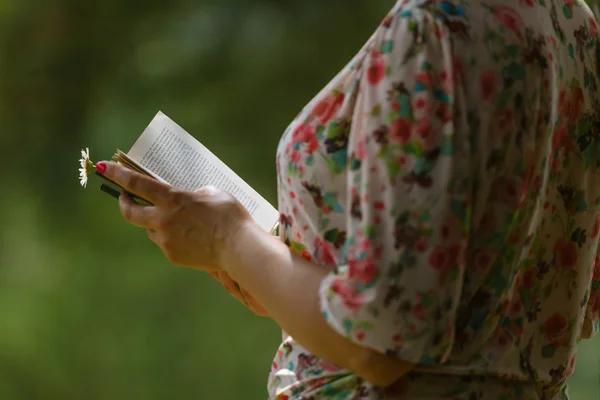 Woman\'s hand holding book in the park.