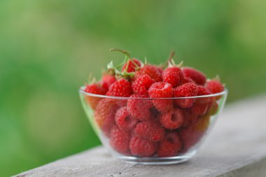 Taze bir güverte raili üzerinde oturan bir cam kabın içinde ahududu aldı