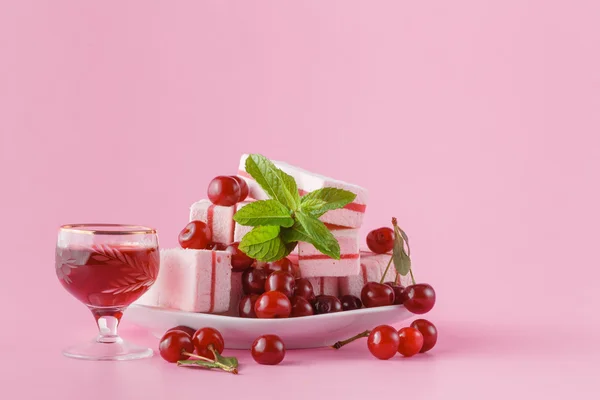 Cherry liquer and sweets on pink background — Stock Photo, Image