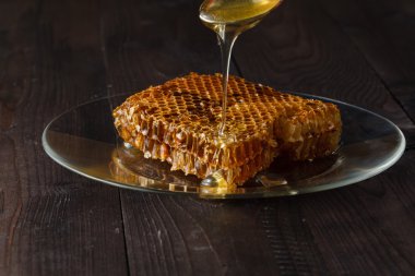 Ahşap gri rustik arka plan tabağa damlayan bal