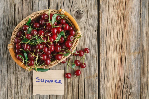 Čerstvé třešně v koši s značku a text léto — Stock fotografie