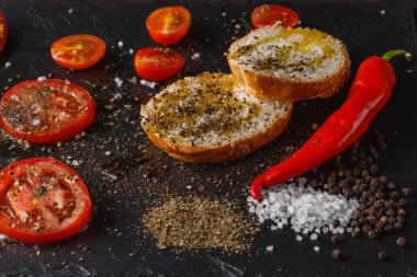 Kırmızı domates biberiye ve zeytinyağı ile. Üzerinde siyah rustik backg