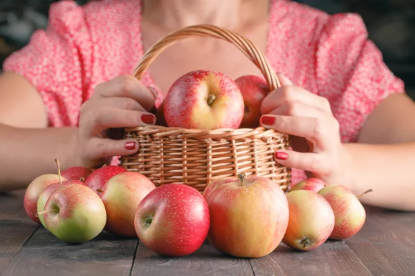 Mujer sosteniendo cesta llena de manzanas — Foto de Stock
