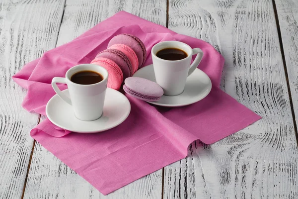 Две чашки кофе эспрессо с макаронами на розовом фоне — стоковое фото