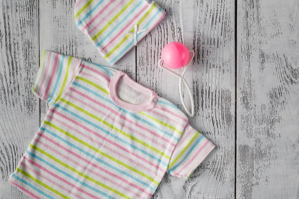 Camisa de bebê na área de trabalho de madeira. Faz asneira. — Fotografia de Stock