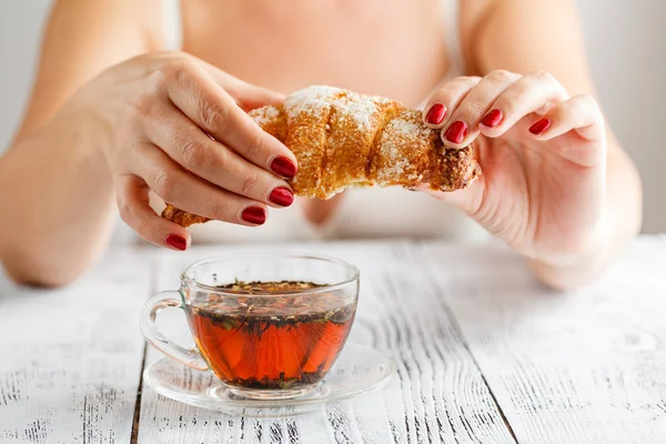 Mulher tomando café da manhã com croissants de manhã em casa interi — Fotografia de Stock