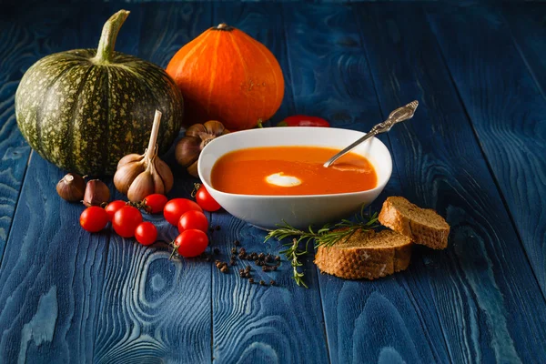Pumpkin soup in a bowl with fresh pumpkins, garlic and parsley h — Stock Photo, Image