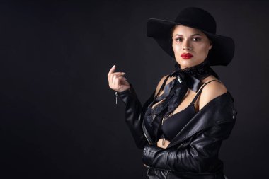 Büyük siyah şapkalı ve ceketli bir kadın, stüdyo resmi, koyu arkaplan