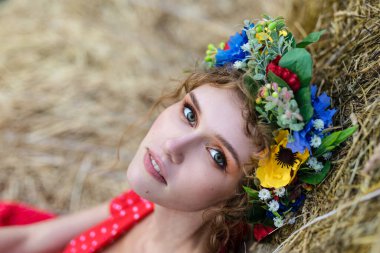 Kırmızı elbiseli güzel bir mankenin portresi güneşli bir sonbahar gününde samanlıklarda poz veriyor. Sonbahar sıcak fotoğrafı