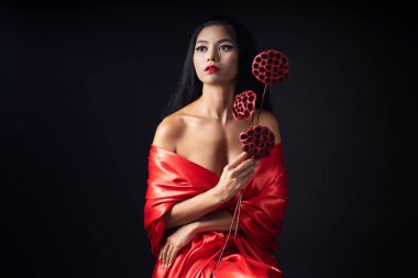 Kırmızı dudaklı ve geleneksel kırmızı Çin elbisesi giyen siyah arkaplanlı Çinli bir kız.