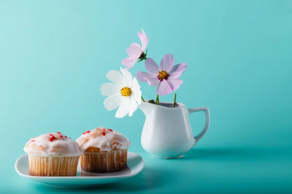 Muffin colorido en platillo con flor. Fondo de color aqua — Foto de Stock