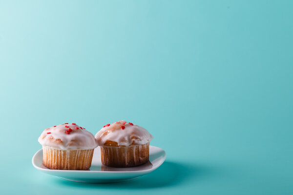 Colorful muffin on saucer. Aqua color plain background