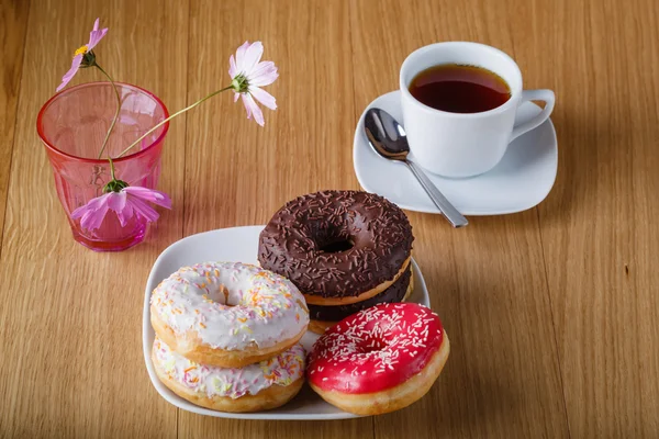 Deliciosas rosquillas en la mesa de madera con taza de té — Foto de Stock