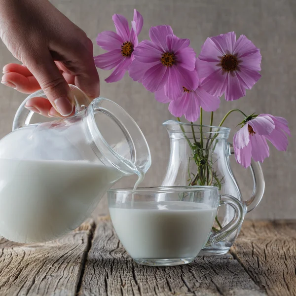 Hälsosam mat koncept. Kopp mjölk på träbord med blommor — Stockfoto