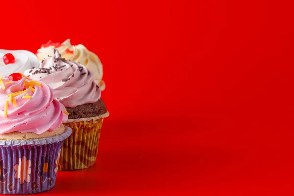 Brigth kırmızı arka plan üzerinde renkli cupcake — Stok fotoğraf