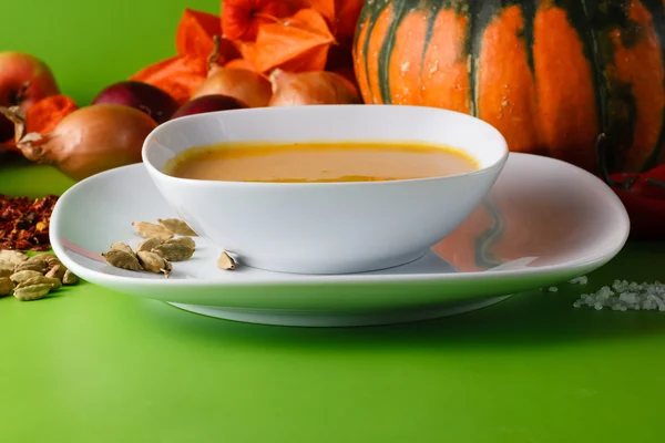 Sopa de abóbora com cebola e pimenta em backgroud sem sombra verde — Fotografia de Stock