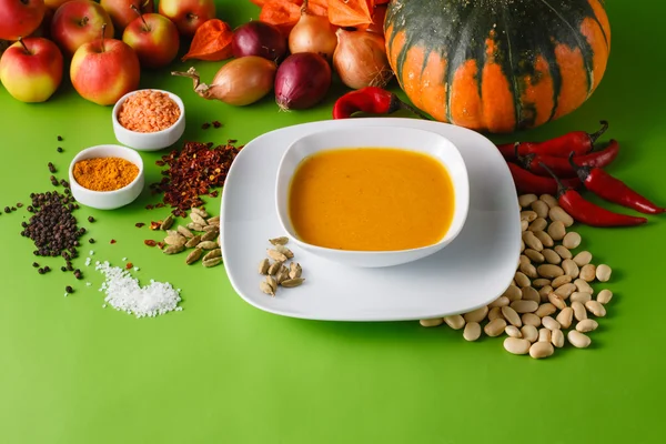 Sopa de abóbora com cebola e pimenta em backgroud sem sombra verde — Fotografia de Stock