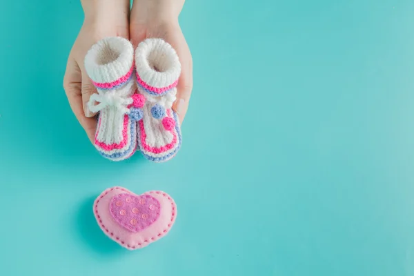 Hand holding tiny knitted booties — Stock Photo, Image