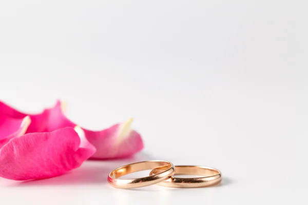 Pétalos de rosa y anillos de boda de oro — Foto de Stock