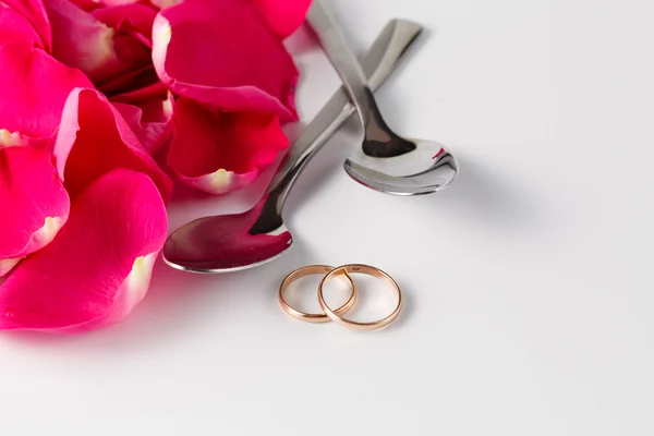 Pétalos de rosa y anillos de boda de oro — Foto de Stock