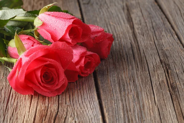 Ramo de rosas sobre mesa de madera vieja — Foto de Stock