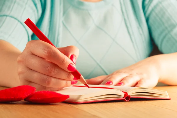 Main de femme dessin ou écriture, boîte cadeau, coeurs rouges sur t en bois — Photo