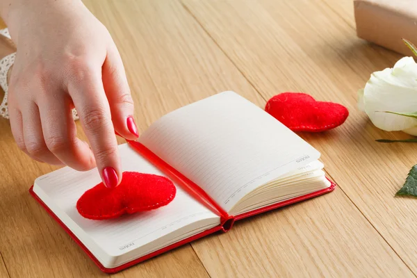 As mãos femininas tocam o coração vermelho no diário do dia de Valentim com g — Fotografia de Stock