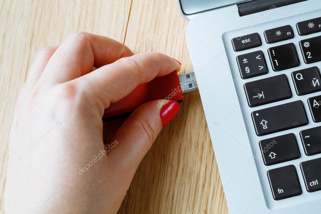 Close up of a woman hand plugging a pendrive on a laptop