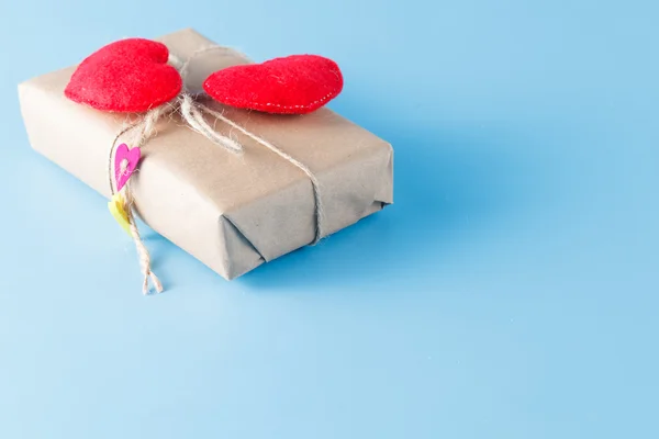 Un paquete de papel envuelto atado. Un corazón rojo en una caja de regalo — Foto de Stock