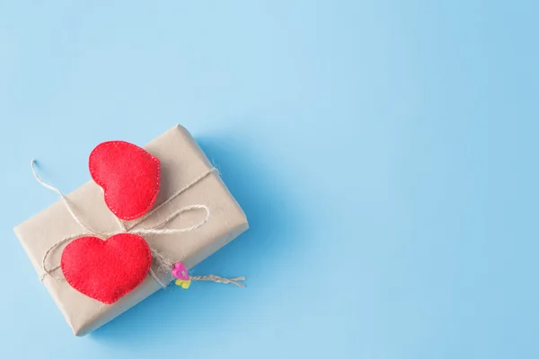 Um pacote de papel embrulhado amarrado. Um coração vermelho em uma caixa de presente — Fotografia de Stock