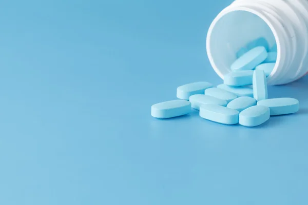 Blue pills an pill bottle on blue background — Stock Photo, Image