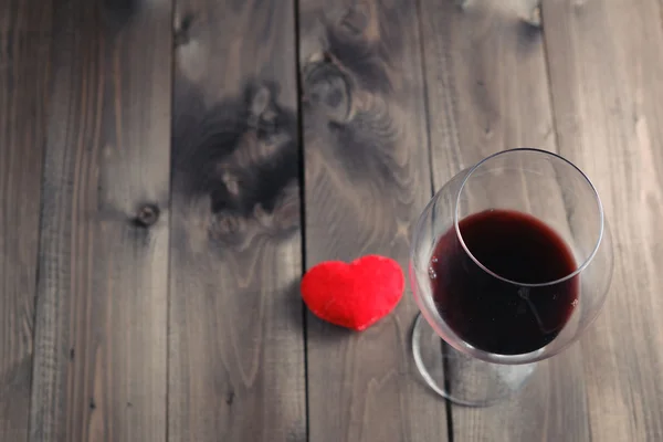 Copa de vino tinto sobre mesa de madera y corazón —  Fotos de Stock