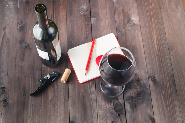 Copo de vinho tinto e caderno na mesa — Fotografia de Stock