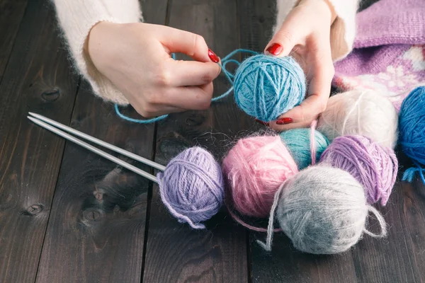 Female hands with purple manicure are knitted metal spokes of a