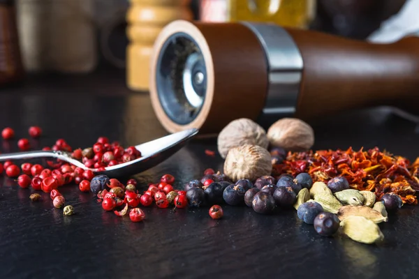 pepper mill with pepper on a slate background