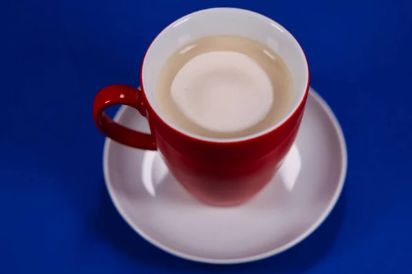 Red cup of fresh coffee with blue background.