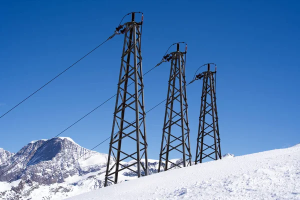 Three towers with cables delivering electric energy supply for alpine cable cars an Gornergrat railway. Photo taken March 23rd, 2021, Zermatt, Switzerland.