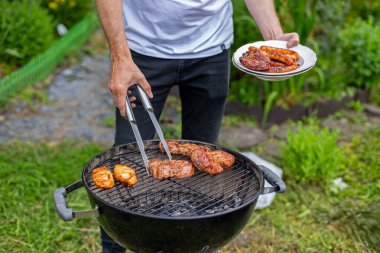 Man Grilling Meat Outdoor 'da mangal yapıyor. Bahçe bahçesinde kömür mangalında ızgara yapan bir adam açık hava yaz pikniğine hazırlanıyor.