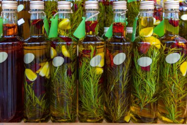 Bottles of infused olive oil with herbs and garlic. Close-up of glass bottles filled with olive oil infused with rosemary, garlic, and chili peppers, ideal for gourmet cooking themes