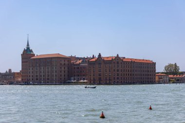 Venedik, İtalya, 11 Ağustos 2025: Giudecca Adası 'ndaki tarihi Molino Stucky Binası. Venedik 'teki Giudecca Adası' ndaki ikonik kırmızı tuğlalı Molino Stucky binasına, açık mavi gökyüzünün altına bakın..