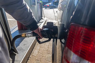 Benzin istasyonunda benzini dolduran kişi. Benzin istasyonunda benzinle doldurulan bir kişinin yakın plan fotoğrafı, yakıt ikmali, ulaşım, enerji kullanımı ve araç servisini gösteriyor